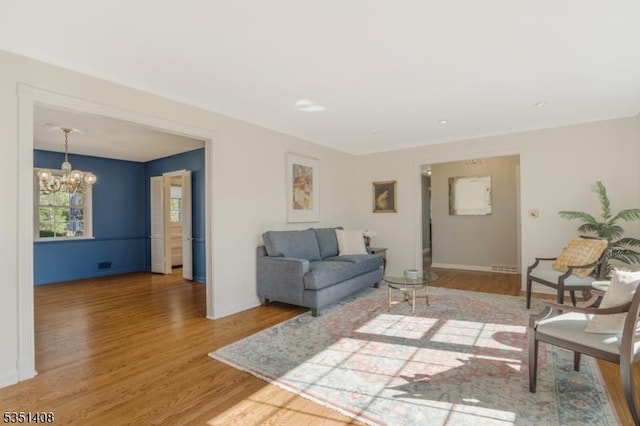 living area featuring baseboards, a notable chandelier, and wood finished floors