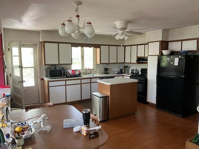 kitchen featuring dark wood-style flooring, a kitchen island, light countertops, white cabinets, and black appliances