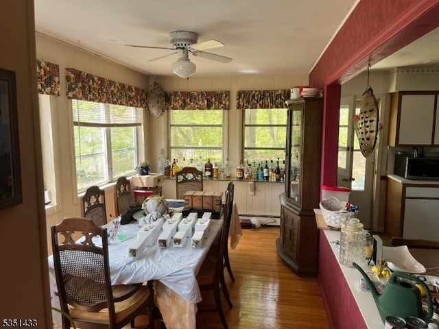 dining area with ceiling fan, wood finished floors, and a baseboard radiator