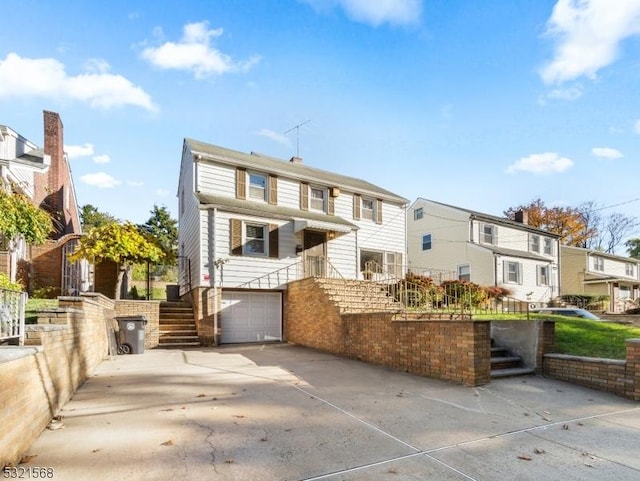 back of house with concrete driveway, stairs, a residential view, and a garage