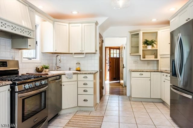 kitchen featuring a sink, appliances with stainless steel finishes, light tile patterned flooring, and a wealth of natural light