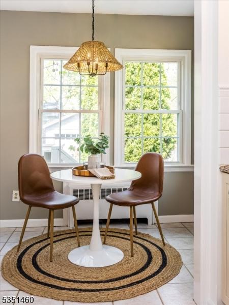dining room with baseboards, breakfast area, light tile patterned floors, and radiator