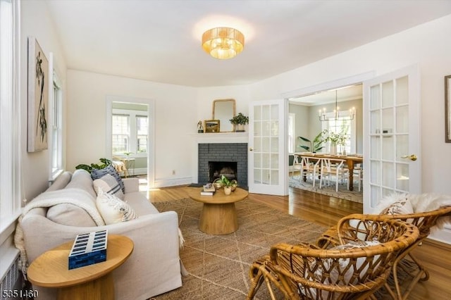 living area with an inviting chandelier, plenty of natural light, a fireplace, and wood finished floors