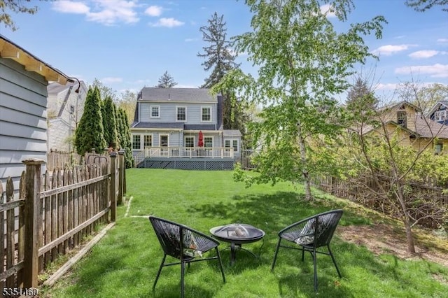 view of yard featuring a fenced backyard, a wooden deck, and a fire pit