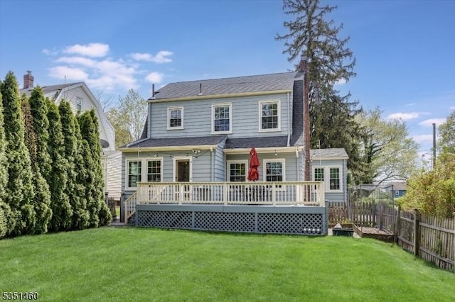 rear view of house featuring a lawn, a chimney, fence, and a deck