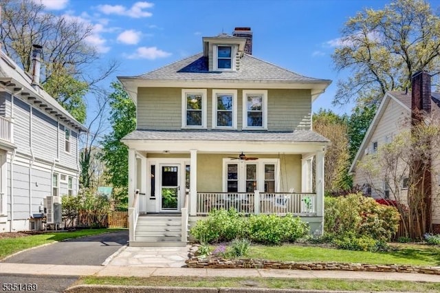 american foursquare style home featuring a porch, a shingled roof, and a chimney