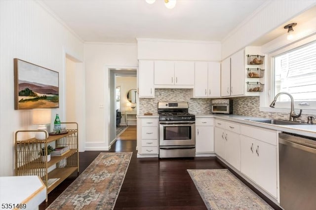 kitchen featuring decorative backsplash, crown molding, appliances with stainless steel finishes, a sink, and light countertops