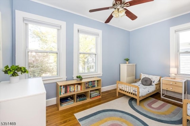 bedroom with baseboards, ornamental molding, and wood finished floors