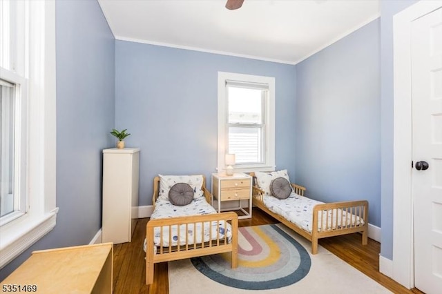 bedroom with crown molding, baseboards, ceiling fan, and wood finished floors