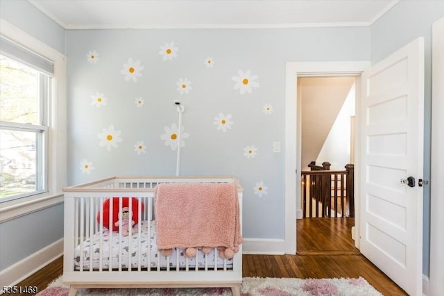 bedroom with crown molding, baseboards, and wood finished floors