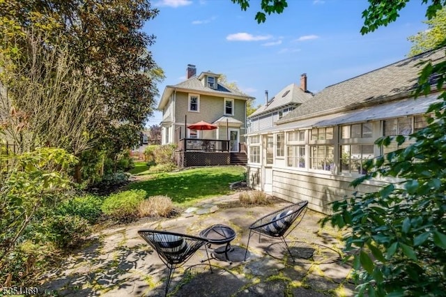 view of yard featuring a sunroom, a deck, and a patio area