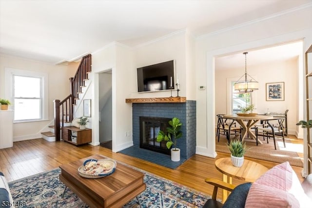 living area with crown molding, a healthy amount of sunlight, wood finished floors, and a fireplace