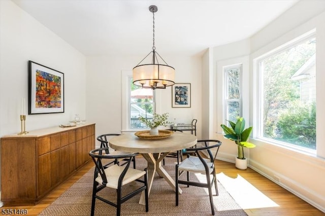 dining area with light wood-style floors, plenty of natural light, an inviting chandelier, and breakfast area