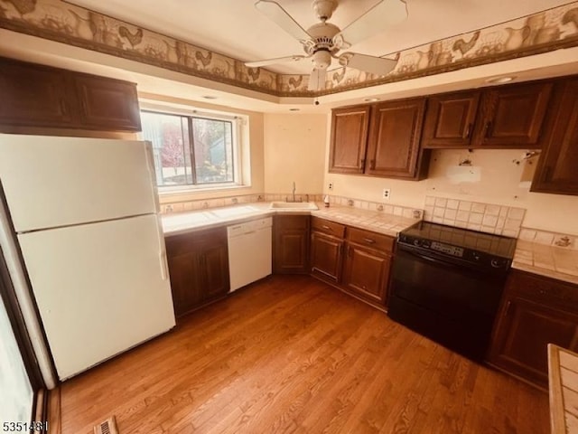 57 Kensington Ct, Washington Twp, NJ 07840 - kitchen with light wood-style floors, tile countertops, a sink, and white appliances
