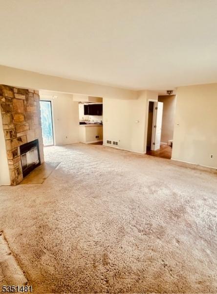 57 Kensington Ct, Washington Twp, NJ 07840 - unfurnished living room with visible vents, a stone fireplace, and carpet floors