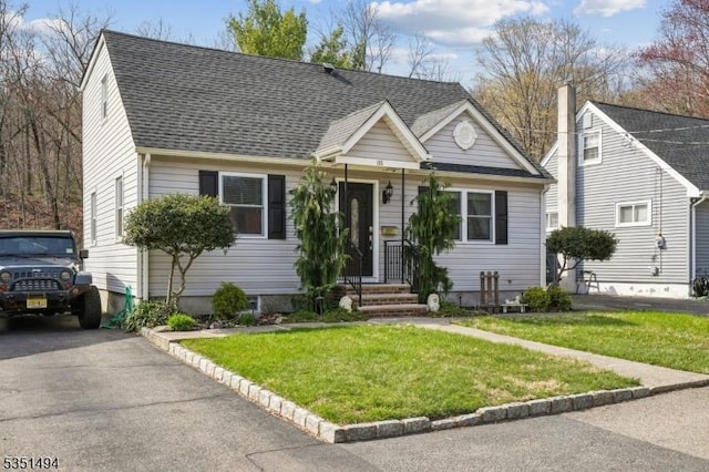 view of front of home with roof with shingles and a front yard