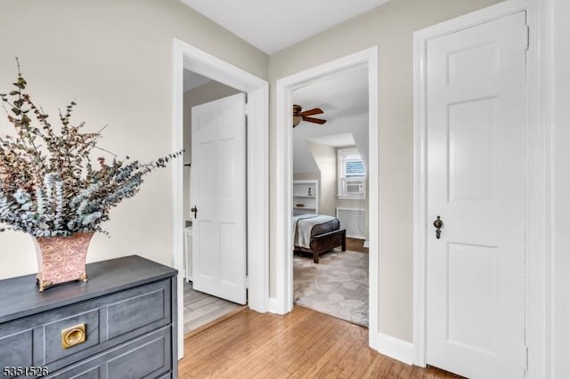 hallway featuring baseboards, cooling unit, and light wood-style flooring