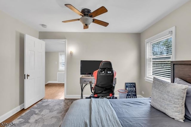 bedroom featuring baseboards, wood finished floors, and multiple windows