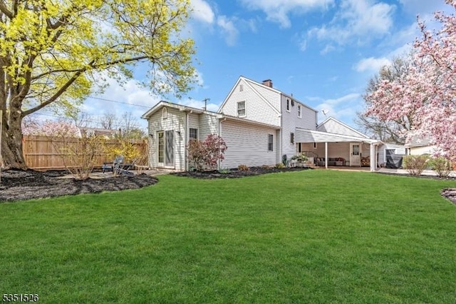 back of property with a yard, a patio, a chimney, and fence