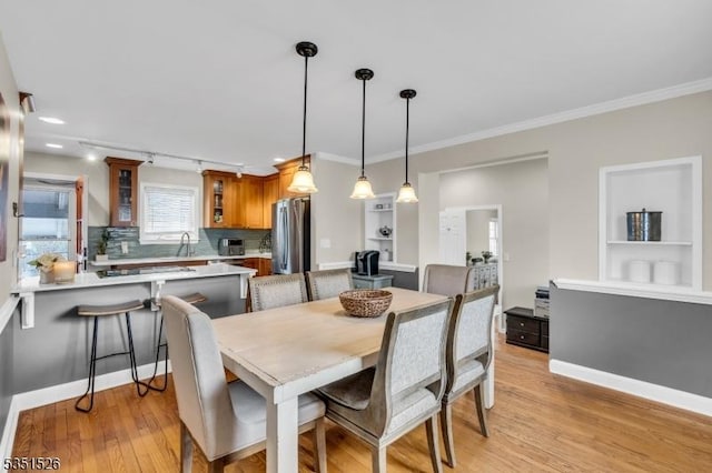 dining room with light wood-type flooring, baseboards, and crown molding