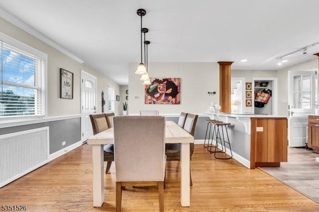 dining area featuring light wood-type flooring, baseboards, ornamental molding, and radiator