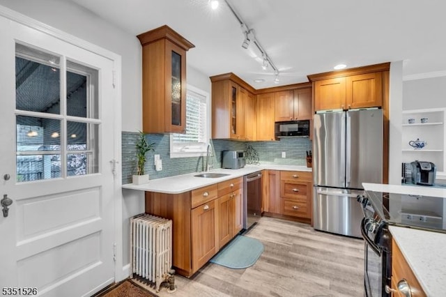 kitchen featuring a sink, radiator, brown cabinetry, light countertops, and black appliances
