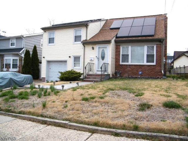 split level home featuring an attached garage, solar panels, and brick siding