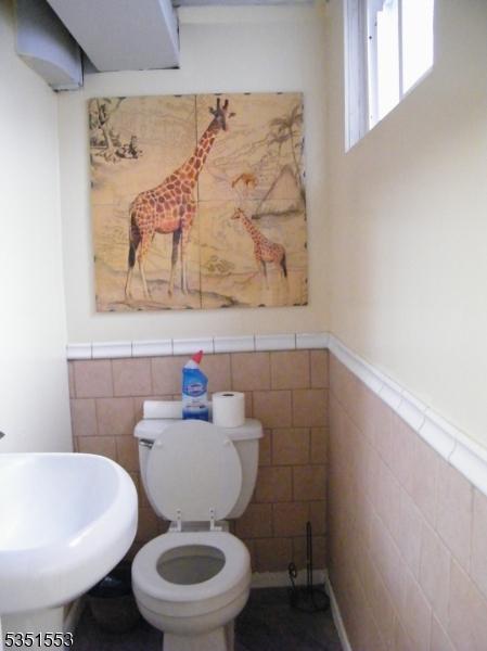 1408 Orchard Ter, Hillside Twp, NJ 07205 - half bath featuring a sink, tile walls, wainscoting, and toilet