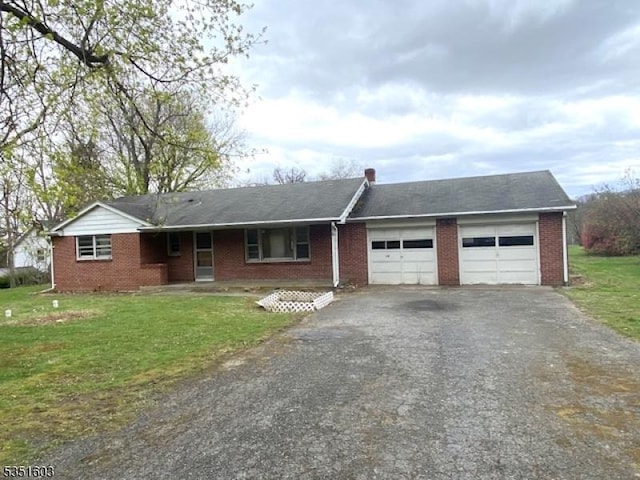 ranch-style house featuring an attached garage, a front yard, driveway, and brick siding