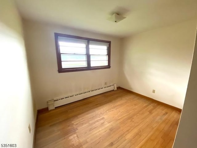 empty room with baseboards, baseboard heating, and light wood finished floors