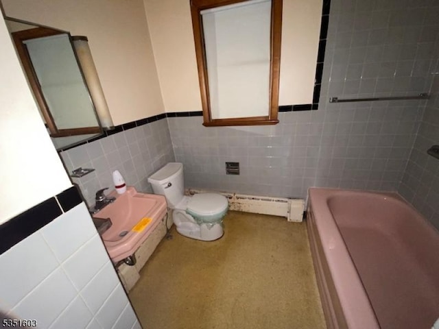 bathroom with toilet, tile walls, a baseboard radiator, a wainscoted wall, and a sink