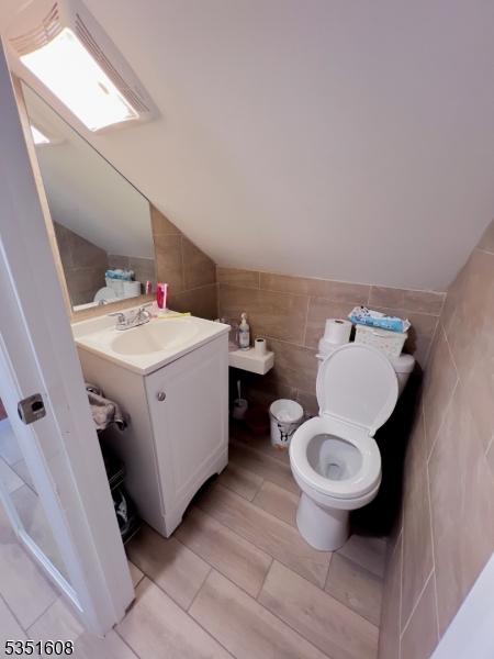 79 Shaler Ave, Fairview Boro, NJ 07022 - bathroom with tile walls, vanity, lofted ceiling, and tile patterned floors