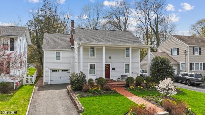 63 Weston Ave, Chatham Boro, NJ 07928 - greek revival house featuring driveway, a chimney, a garage, a shingled roof, and a front yard