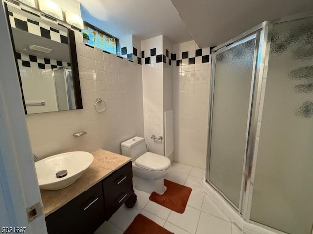 bathroom with vanity, toilet, tile patterned floors, tile walls, and a shower stall