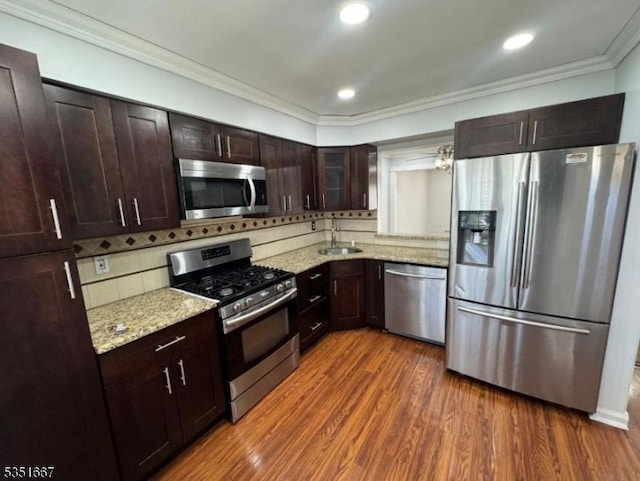 kitchen featuring stainless steel appliances, dark brown cabinetry, decorative backsplash, and a sink