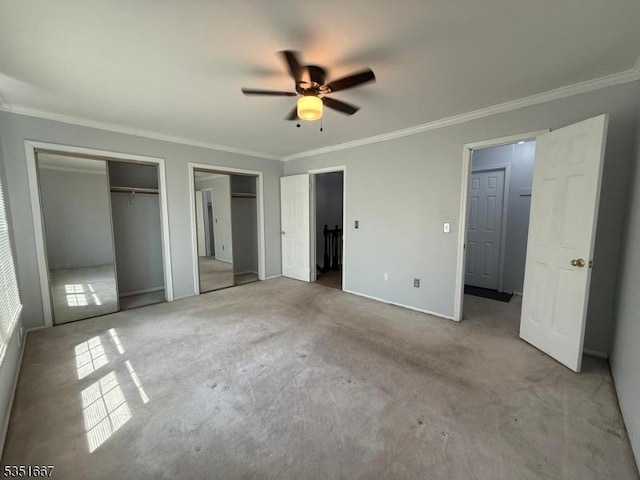 unfurnished bedroom with ceiling fan, multiple closets, carpet, baseboards, and ornamental molding