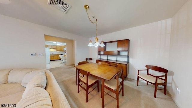 dining room with light colored carpet, a chandelier, and visible vents