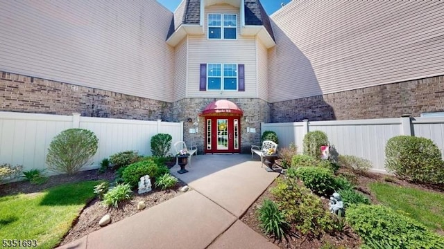 property entrance featuring brick siding, fence, and stone siding