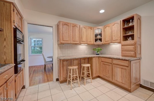 27 Belgrade Ter, West Orange Twp, NJ 07052 - kitchen featuring black oven, a warming drawer, tasteful backsplash, light stone countertops, and light brown cabinets