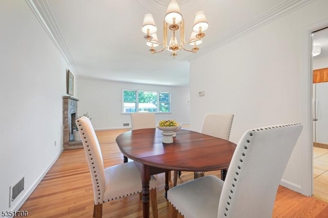 27 Belgrade Ter, West Orange Twp, NJ 07052 - dining room featuring ornamental molding, a chandelier, light wood-style flooring, baseboards, and a stone fireplace