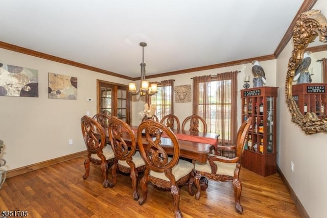 dining room with baseboards, ornamental molding, an inviting chandelier, and light wood-style floors