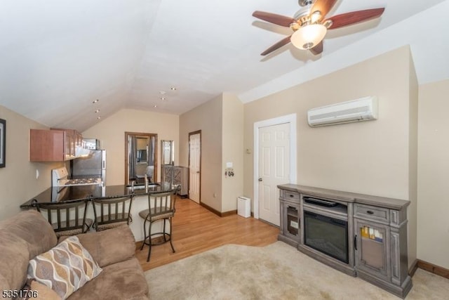 living room with ceiling fan, light wood-style floors, baseboards, an AC wall unit, and vaulted ceiling