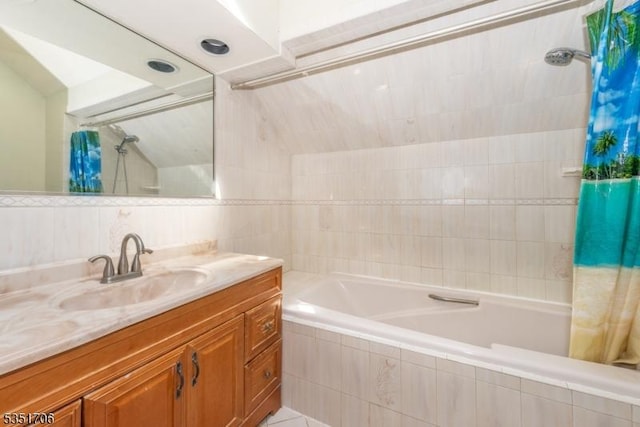 full bathroom featuring lofted ceiling, tiled shower / bath, vanity, and tile walls