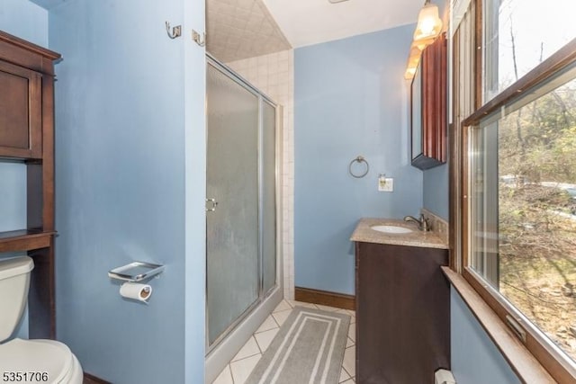 bathroom featuring tile patterned floors, toilet, vanity, and a shower stall