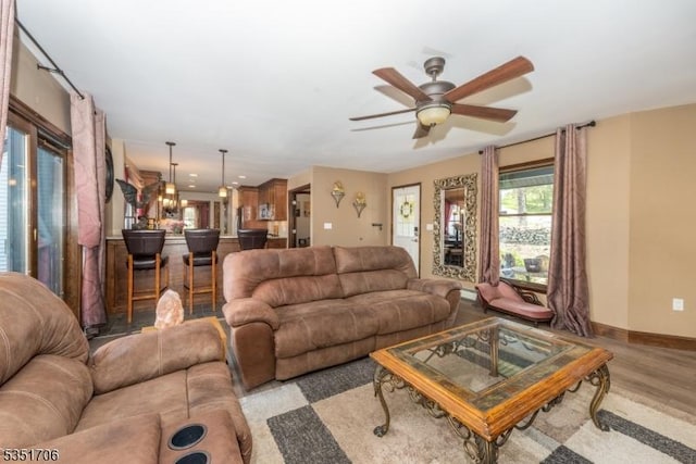 living area with light wood-style floors, a ceiling fan, and baseboards