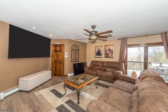 living area with a baseboard heating unit, ceiling fan, baseboards, baseboard heating, and wood finished floors
