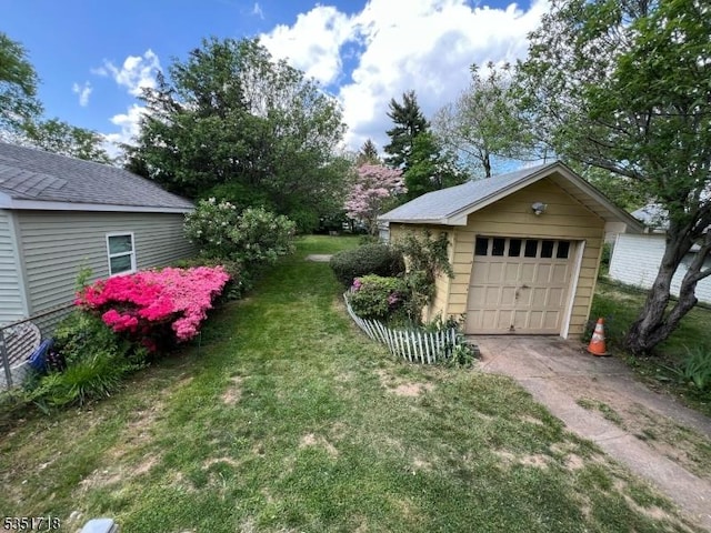 view of yard featuring an outdoor structure, a garage, and concrete driveway
