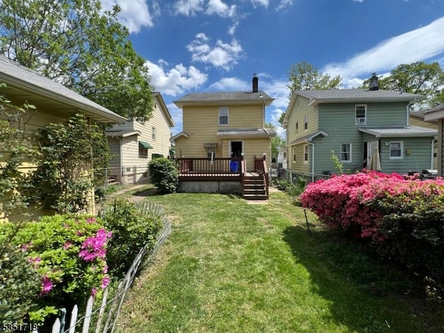 back of property with a lawn, fence, a chimney, and a deck