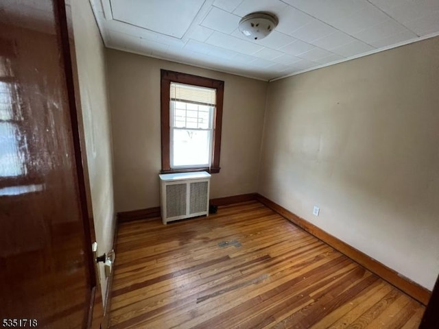 spare room with baseboards, radiator heating unit, and hardwood / wood-style flooring