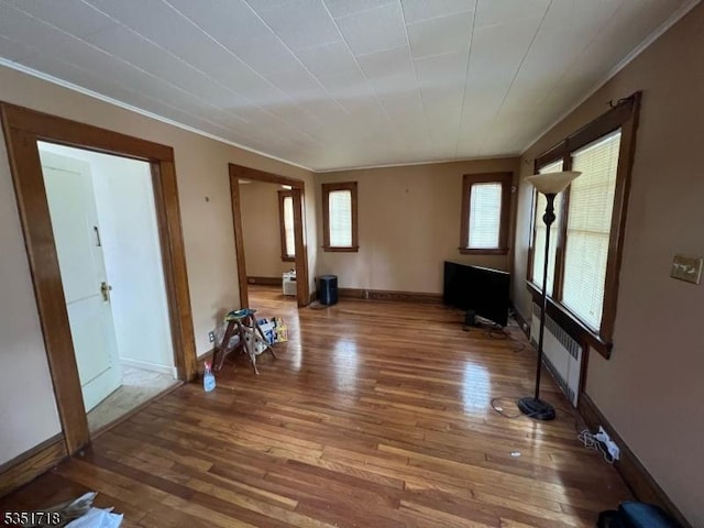 unfurnished living room with ornamental molding, radiator heating unit, and hardwood / wood-style flooring
